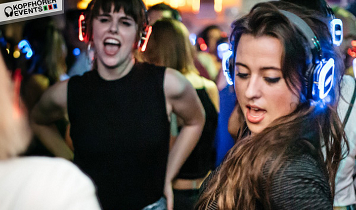 Zwei Frauen die mit bint leuchtenden Kopfhörern bei einer Silent Disco tanzen