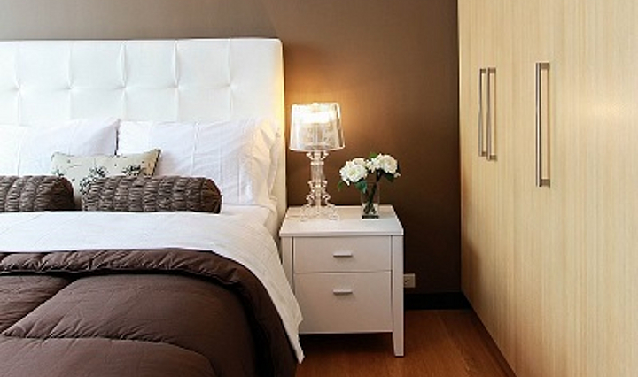 Hotellzimmer mit Bett, Nachttischlampe und Kleiderschrank