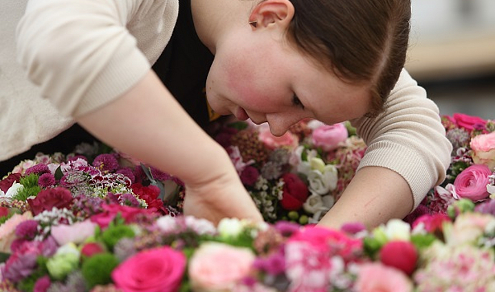 Floristin beim Stecken eines riesigen Kranzes aus Blüten