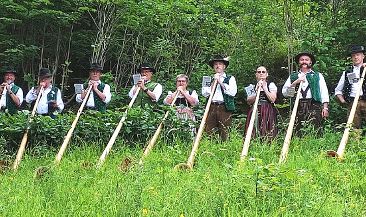 die Alphornbläser "Schwarze Berge" mit Instrumenten in Tracht in der Natur 