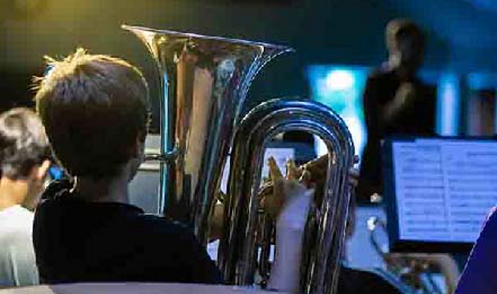 Aufnahme hinter einem Kinderorchester, ein Kind mit Tuba ist im Fokus