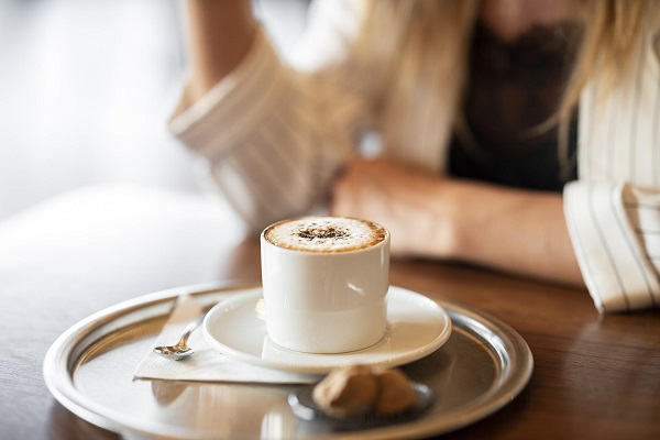 Kaffeetasse mit Praline und Person im Hintergrund